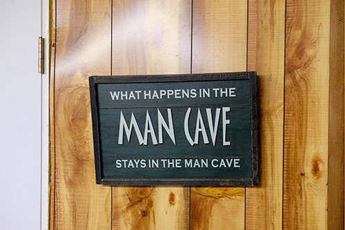 what happens in the man cave stays in the man cave sign board hanging in front of the door